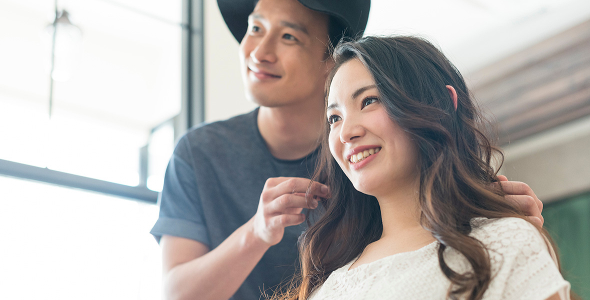 男性美容師に髪を確認されている女性客