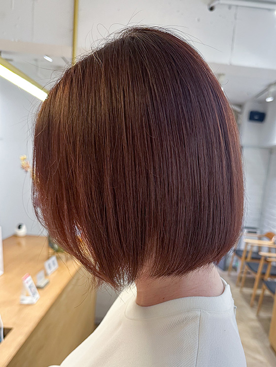 髪色がブラウンピンクの女性の後ろ姿