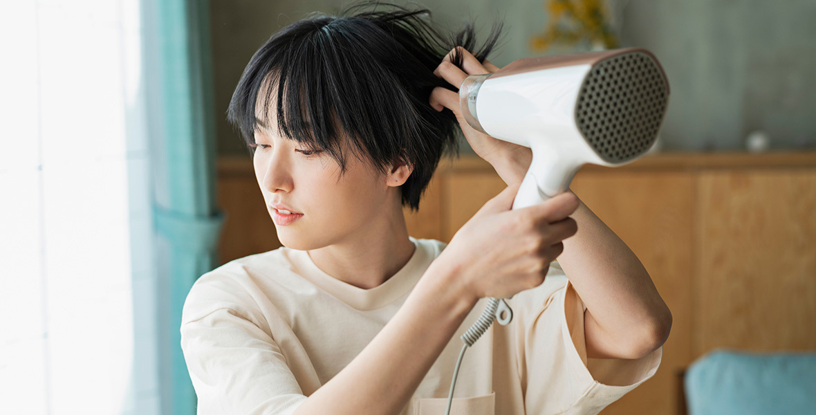 ドライヤーで髪を乾かすショートヘアの女性